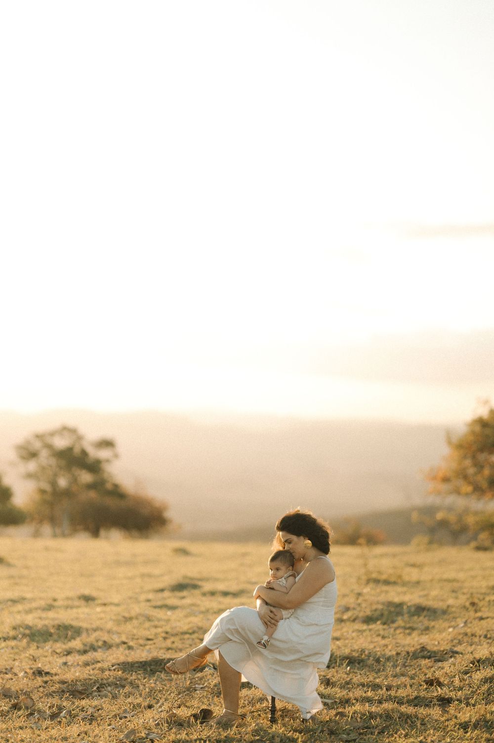 A tender embrace captured during golden hour in a serene meadow landscape.