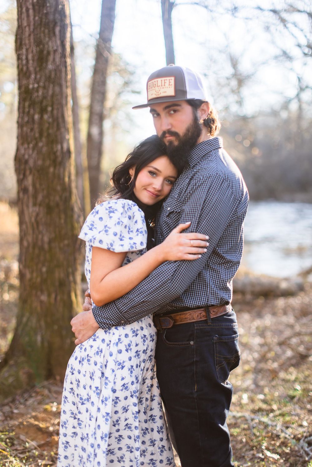 Couple in casual attire shares tender moments during woodland photo session.