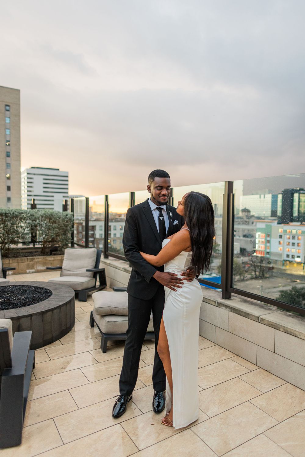 Romantic rooftop moment between couple at sunset with urban view.