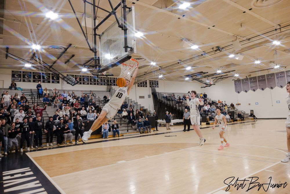 Basketball player makes a leaping shot attempt in a packed high school gymnasium during an intense game.
