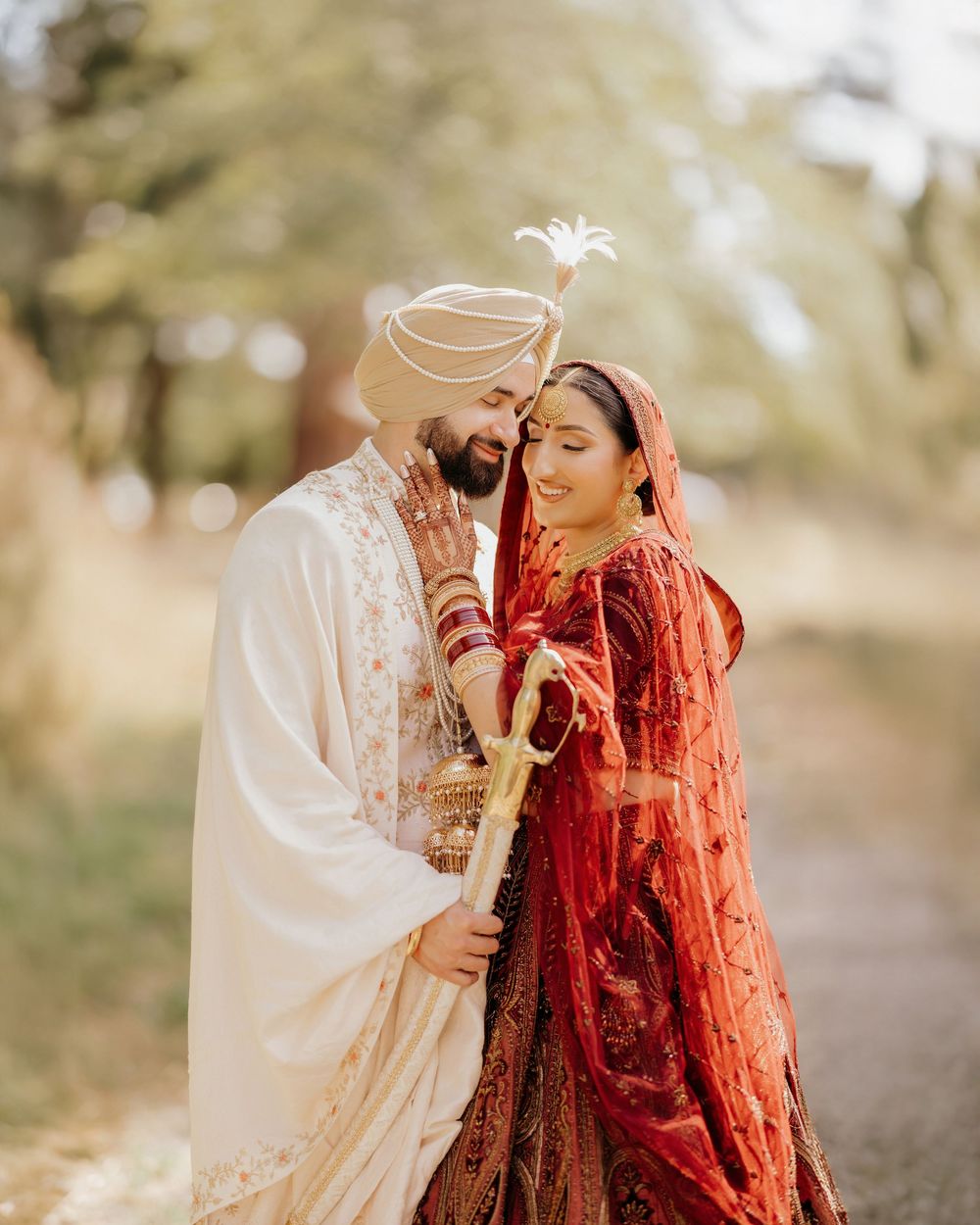 A romantic outdoor wedding portrait showing a couple in traditional Sikh attire against a natural backdrop.