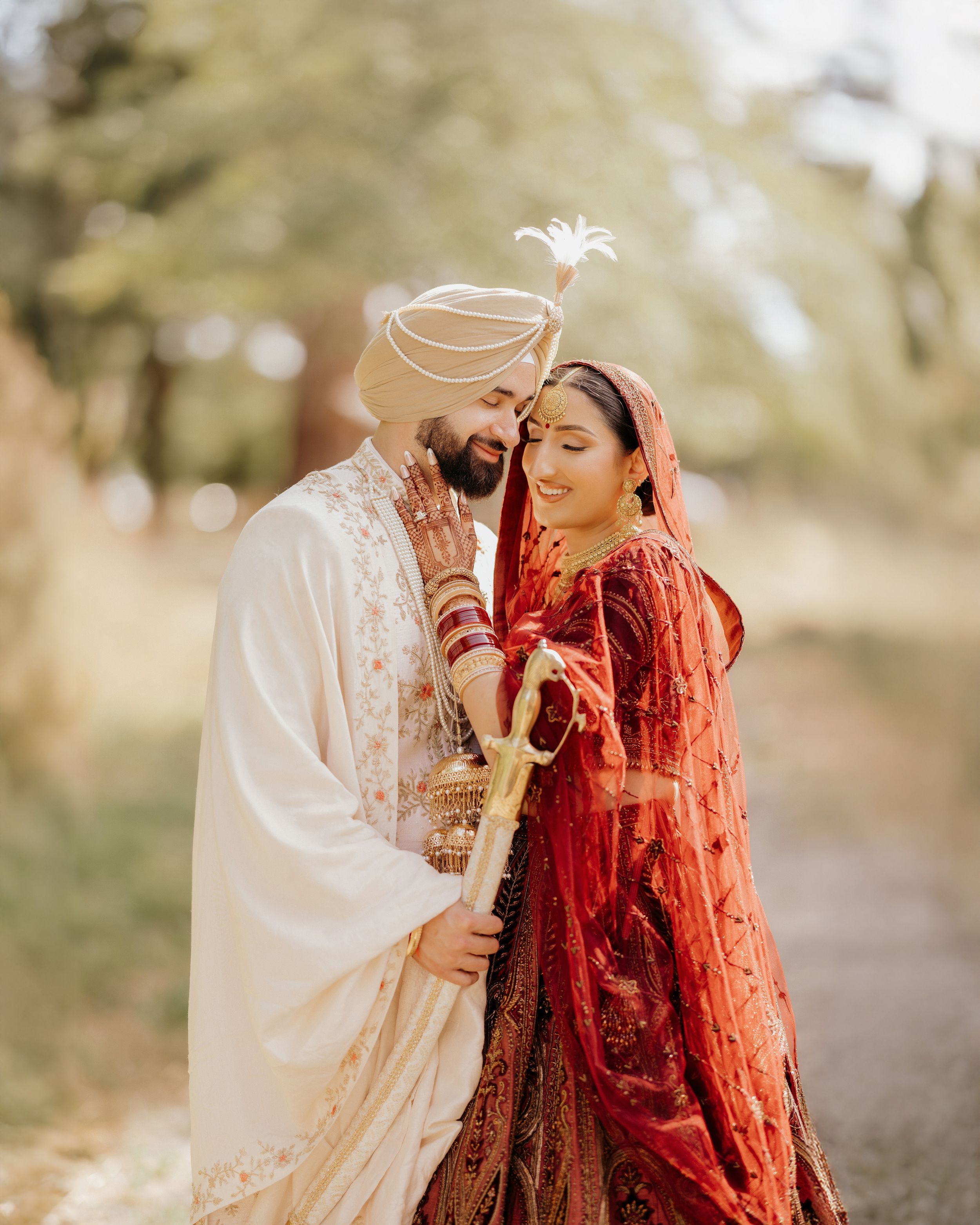 A romantic outdoor wedding portrait showing a couple in traditional Sikh attire against a natural backdrop.