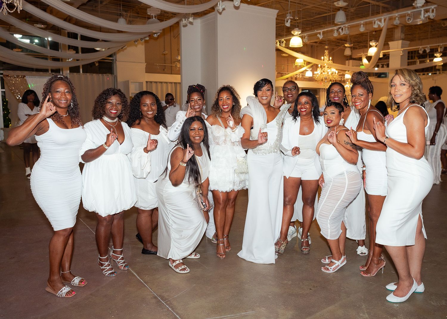 A joyful group in white outfits poses together at a special event.