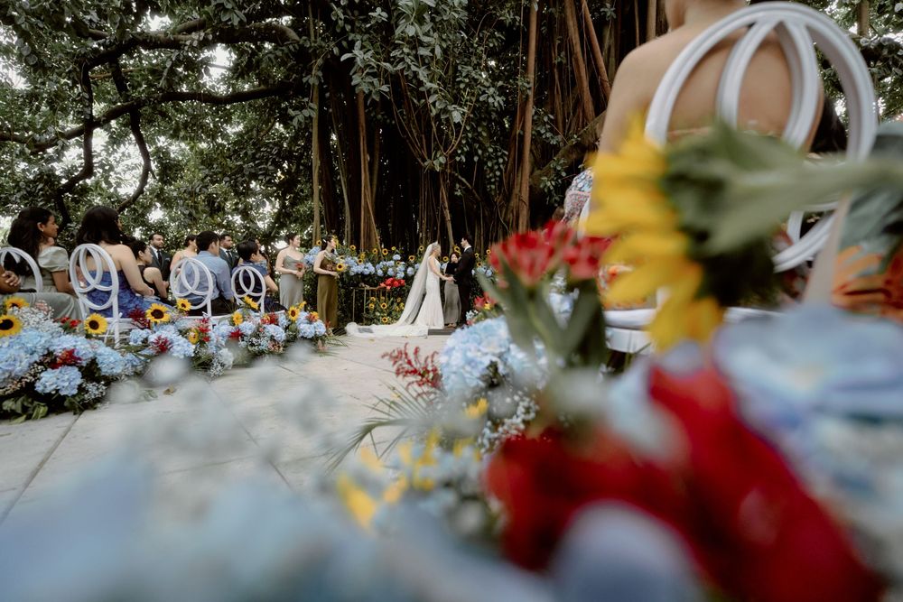 A wedding ceremony setup with colorful flowers and white chairs in an outdoor garden setting.