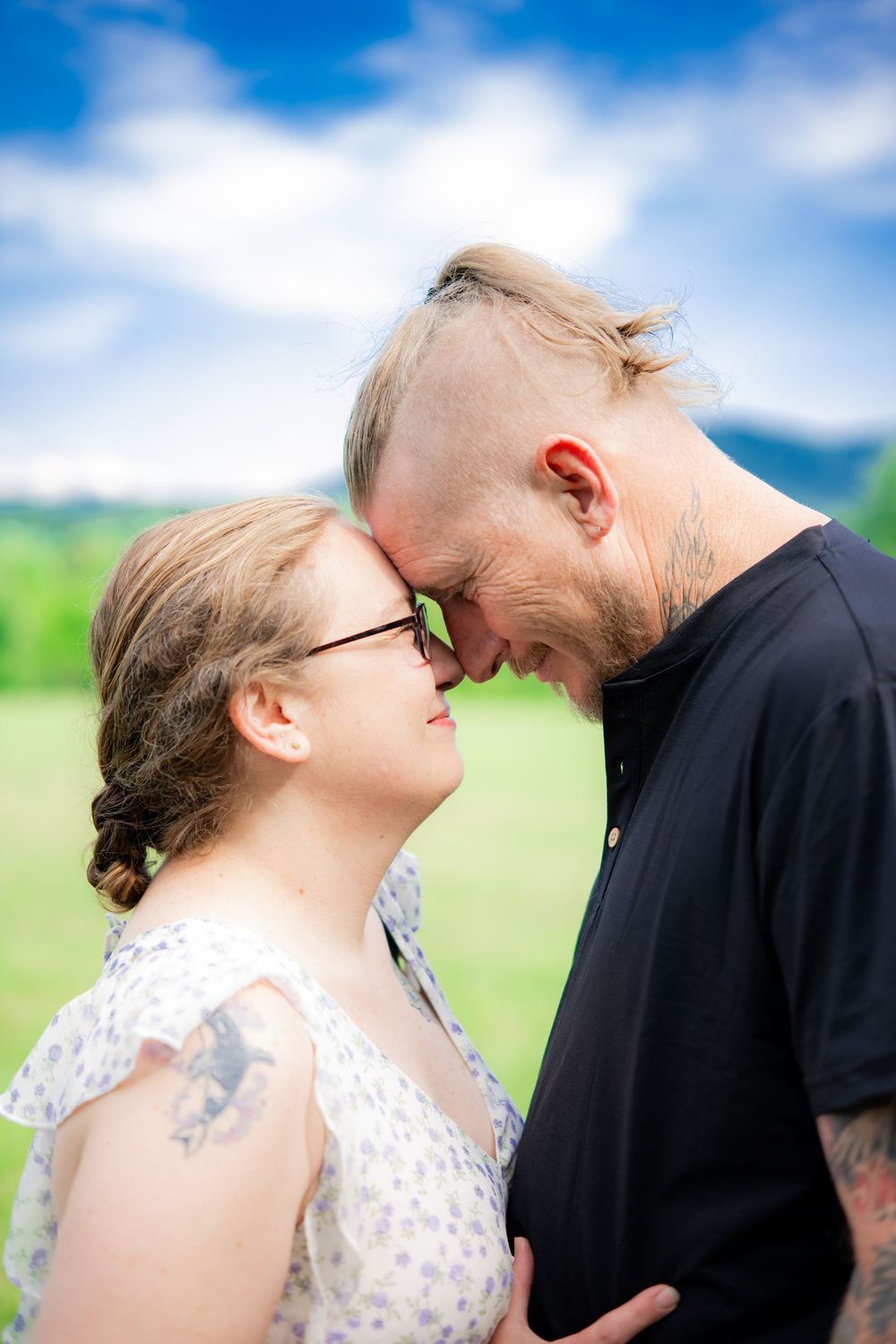 Romantic couple touching foreheads outdoors, green meadow background. Engagement Photographer.