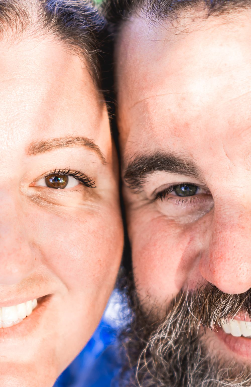 Close-up portrait of a smiling couple with dark hair, the man sporting a beard, cheeks touching pose. Couples Engagement Photographer.