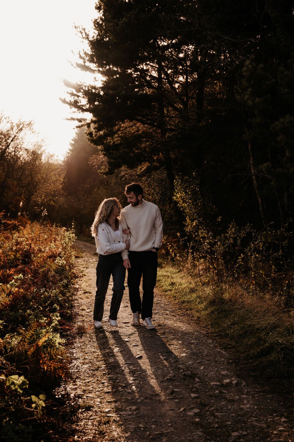Couple walking on a nature trail during golden hour casting long shadows.
