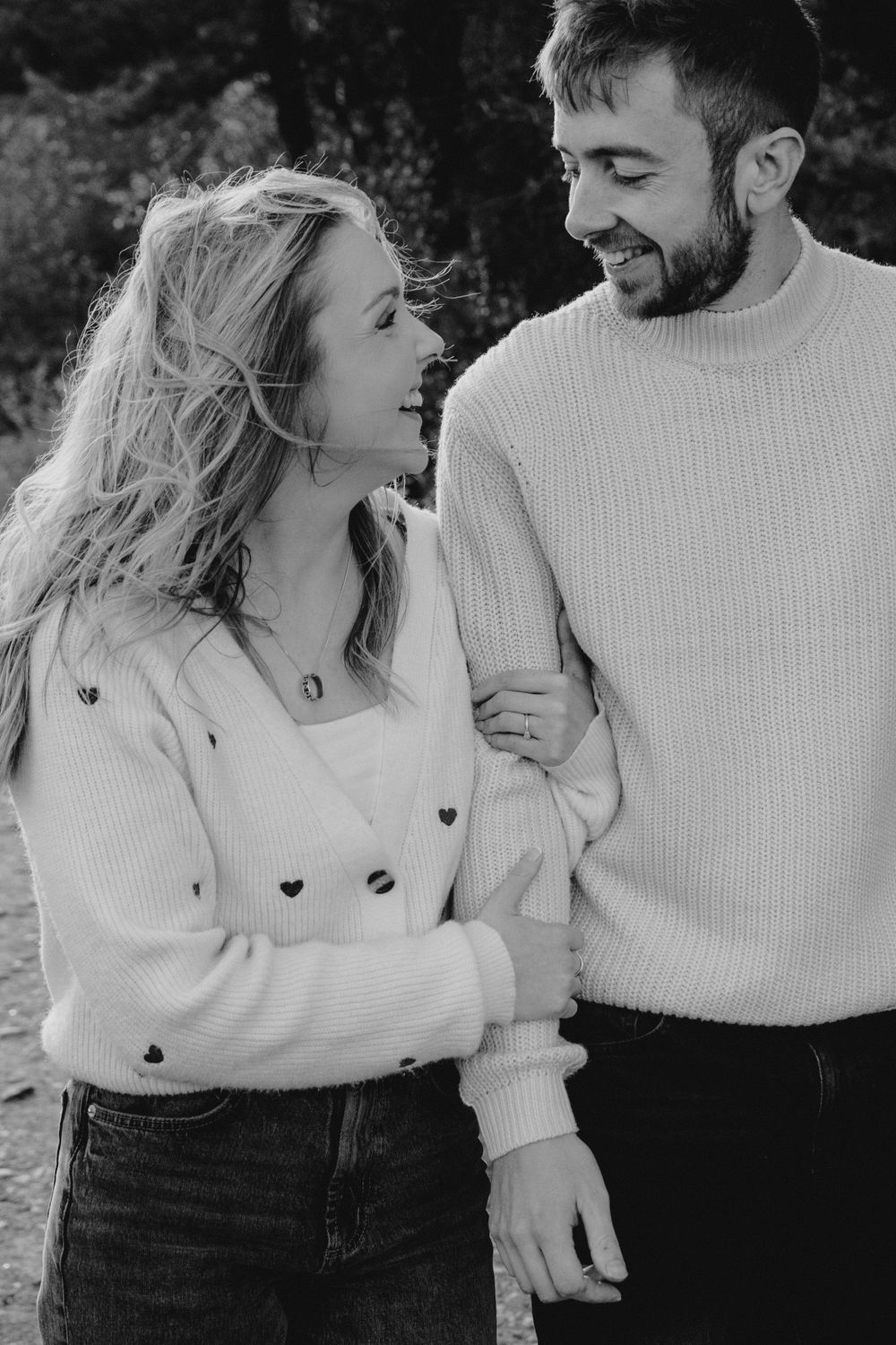 Couple in coordinated white sweaters sharing candid moments outdoors.