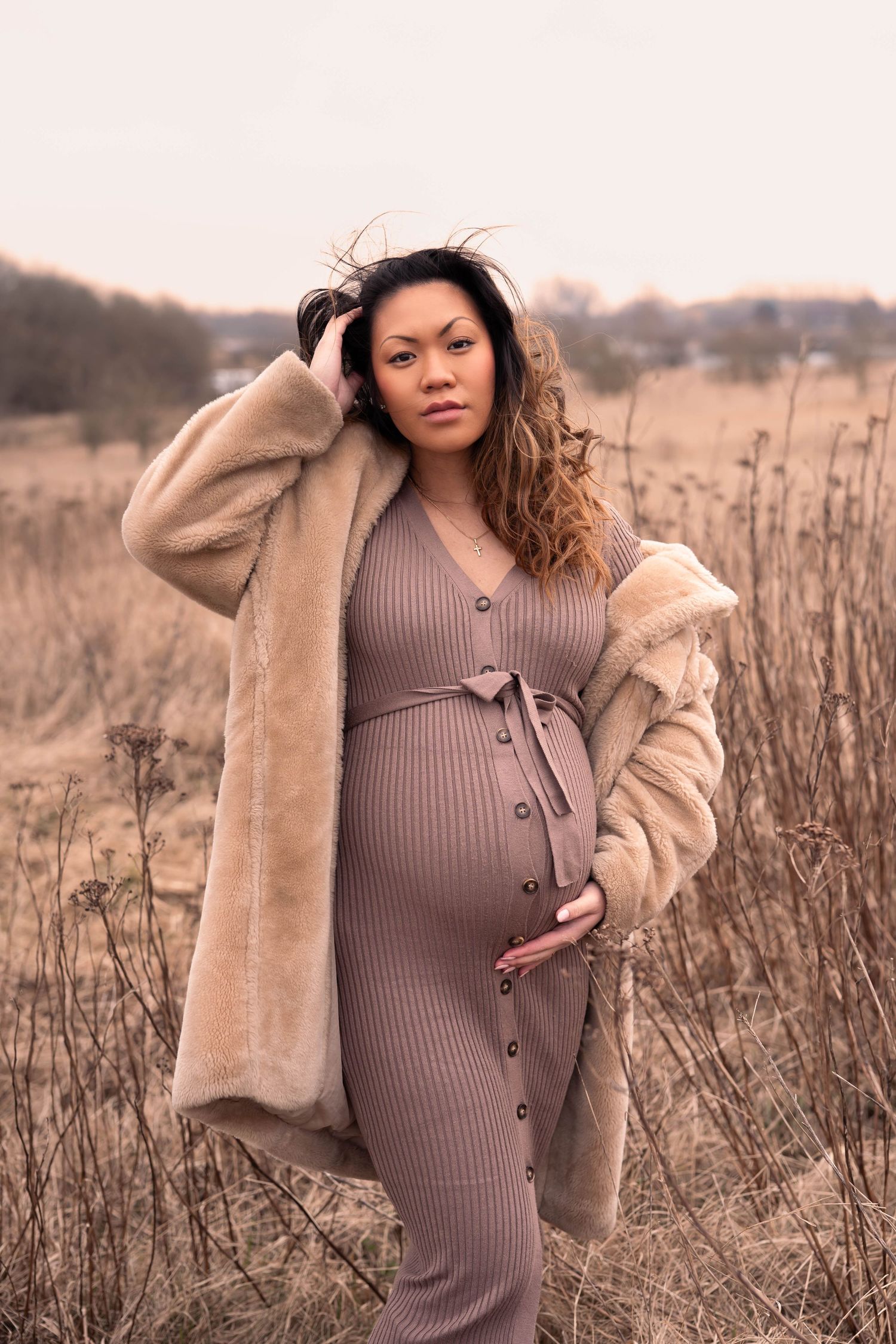 a woman posing in maternity photoshoot on golden field