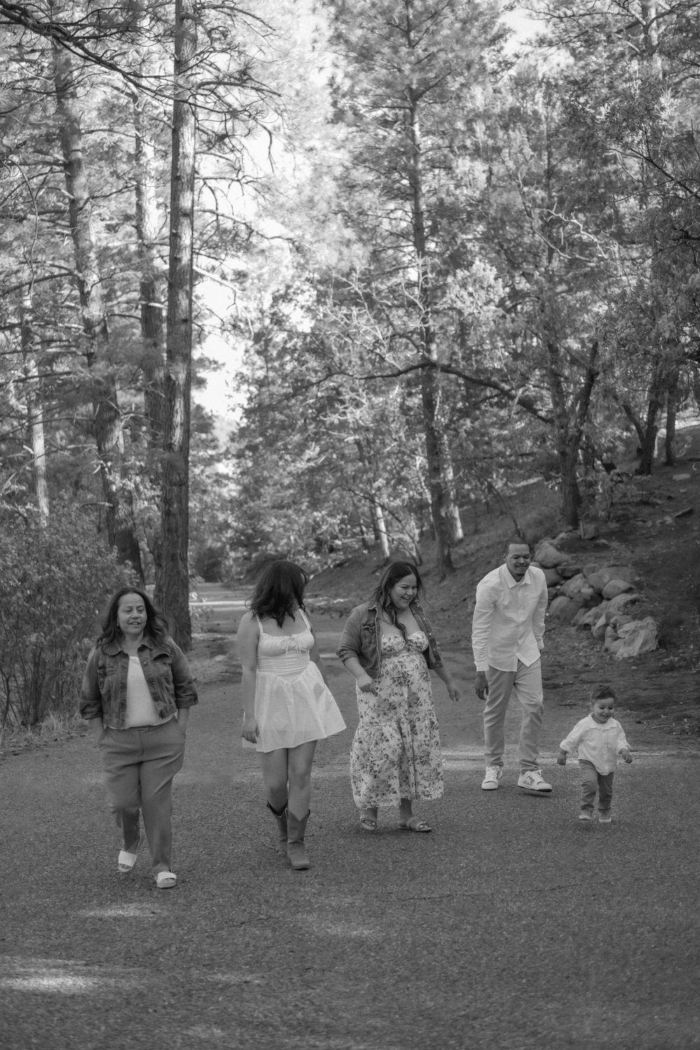 A black and white photo of a family walking together on a forest path in the Sandia Mountains in albuquqerque New Mexico. abq family photos.