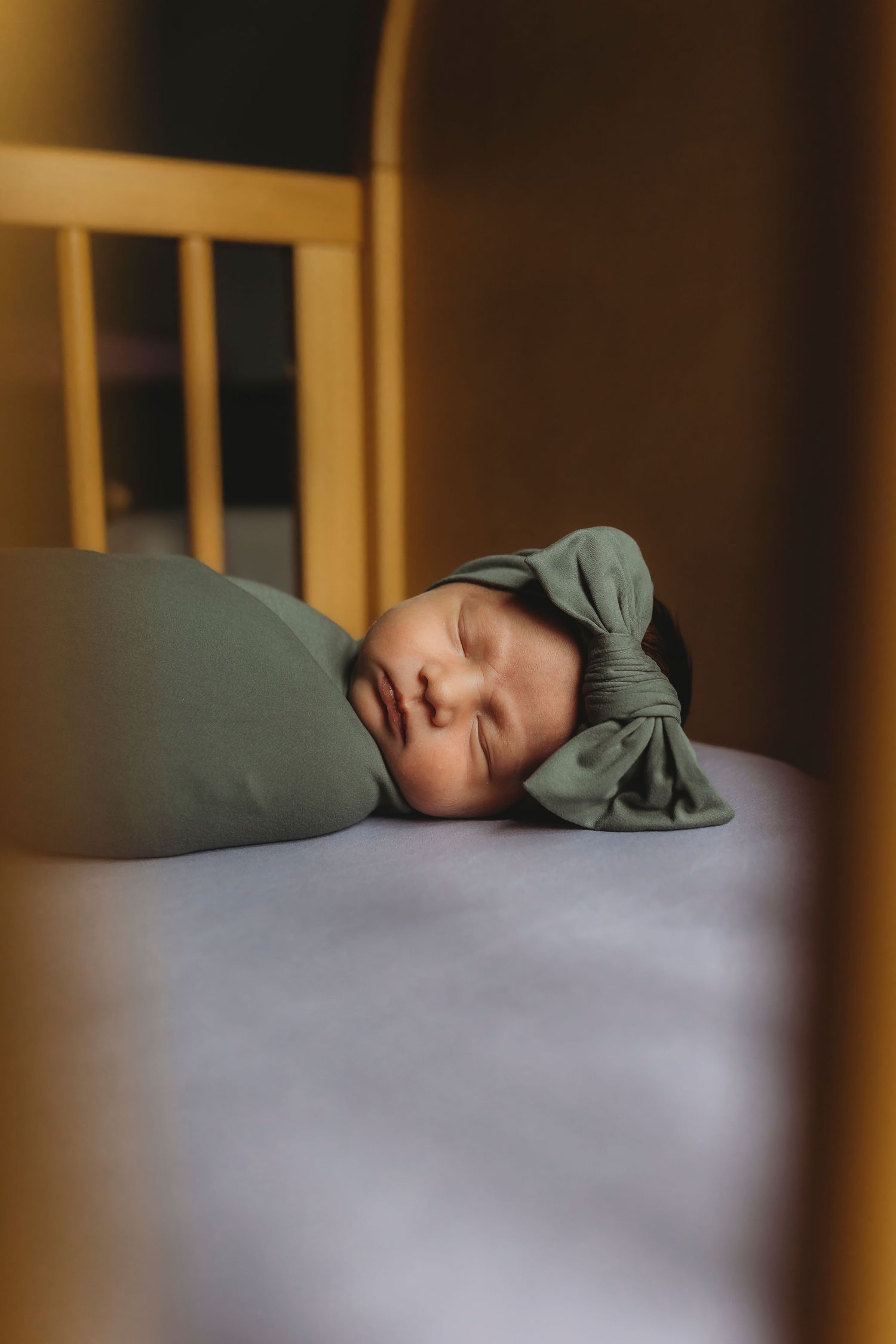A sleeping baby in a green outfit rests peacefully in a crib.