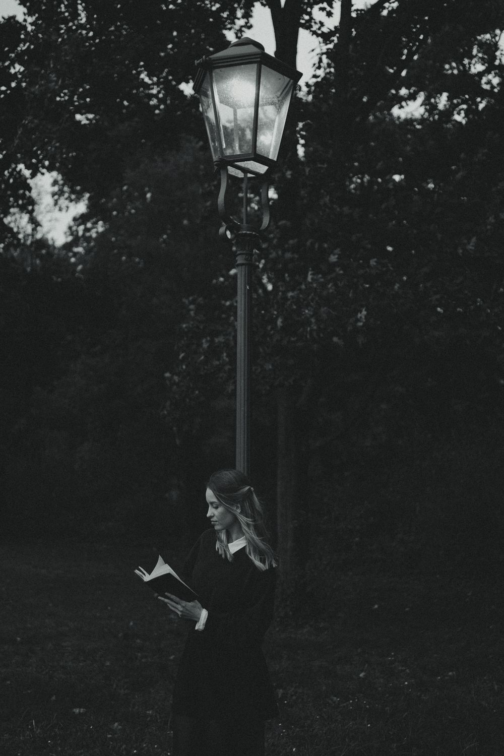 Nostalgisches Portrait Fotoshooting im Abendlicht im Großen Garten Dresden - Frau mit Buch unter leuchtenden Parklaterne
