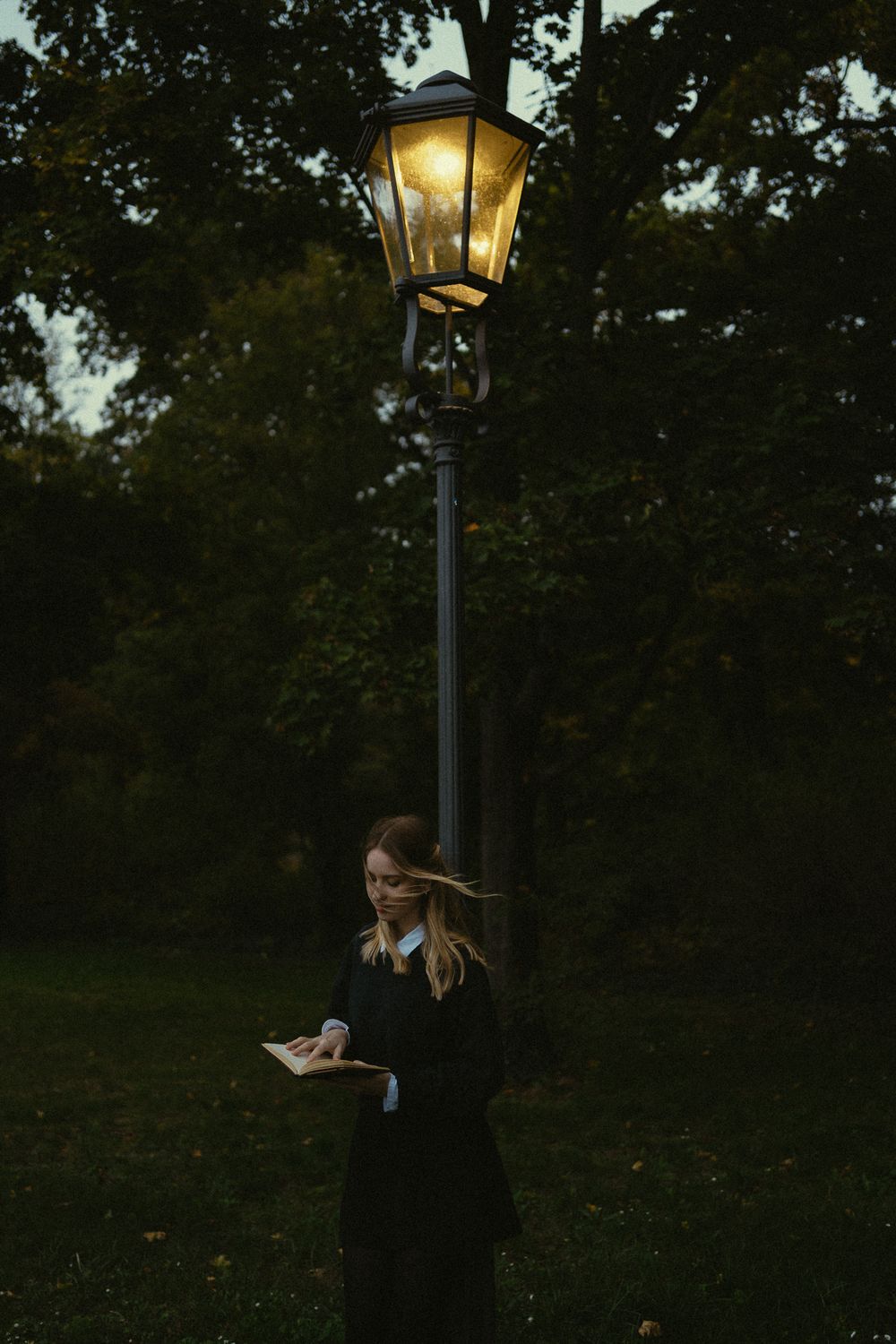 Portrait Fotoshooting einer lesenden Frau unter einer leuchtenden Laterne stehend in Dresden Großer Garten