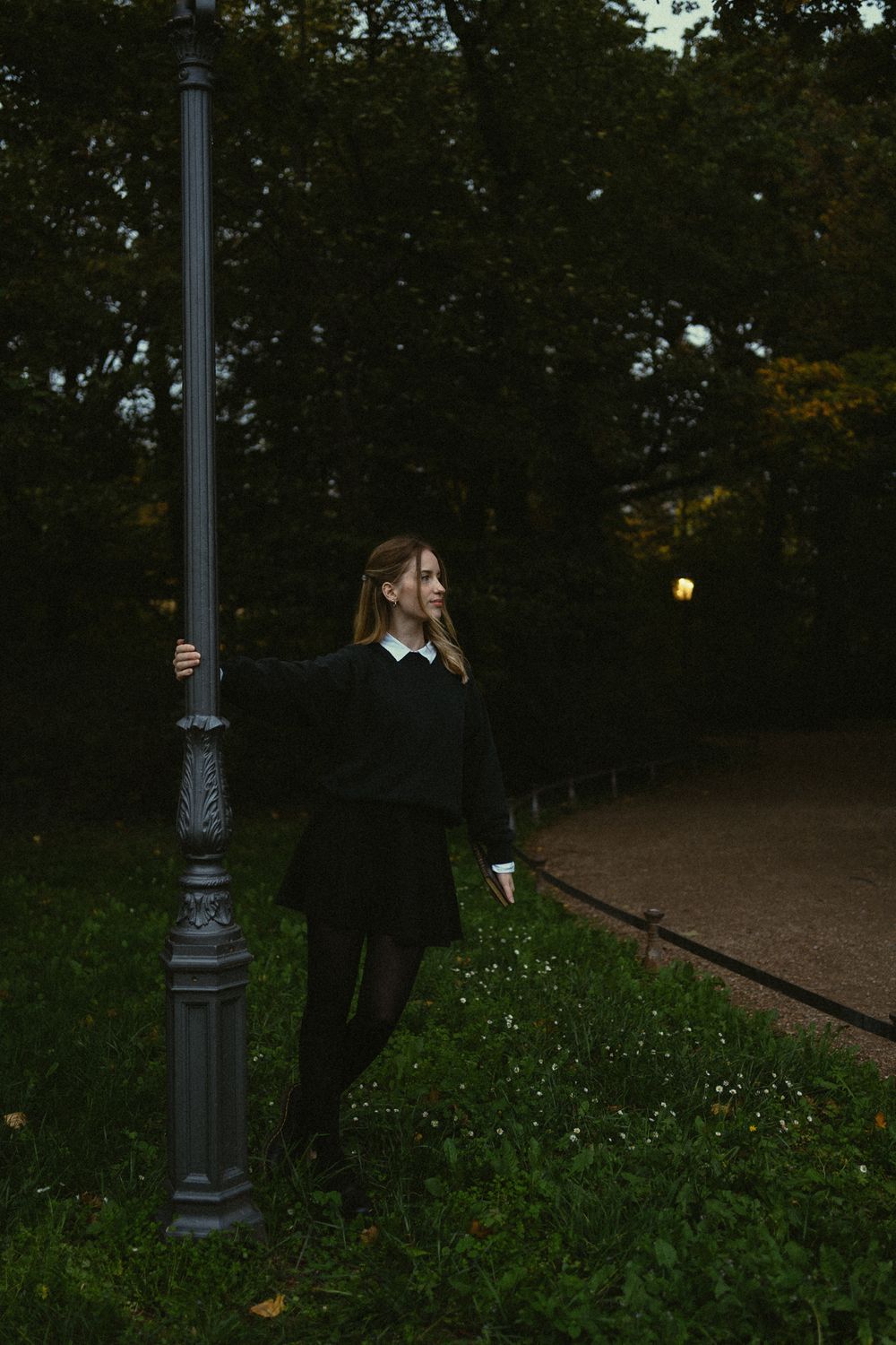 Junge Frau dreht sich um eine Laterne mit Buch in der Hand - Sonnenuntergang Portrait Fotoshooting im Großen Garten Dresden