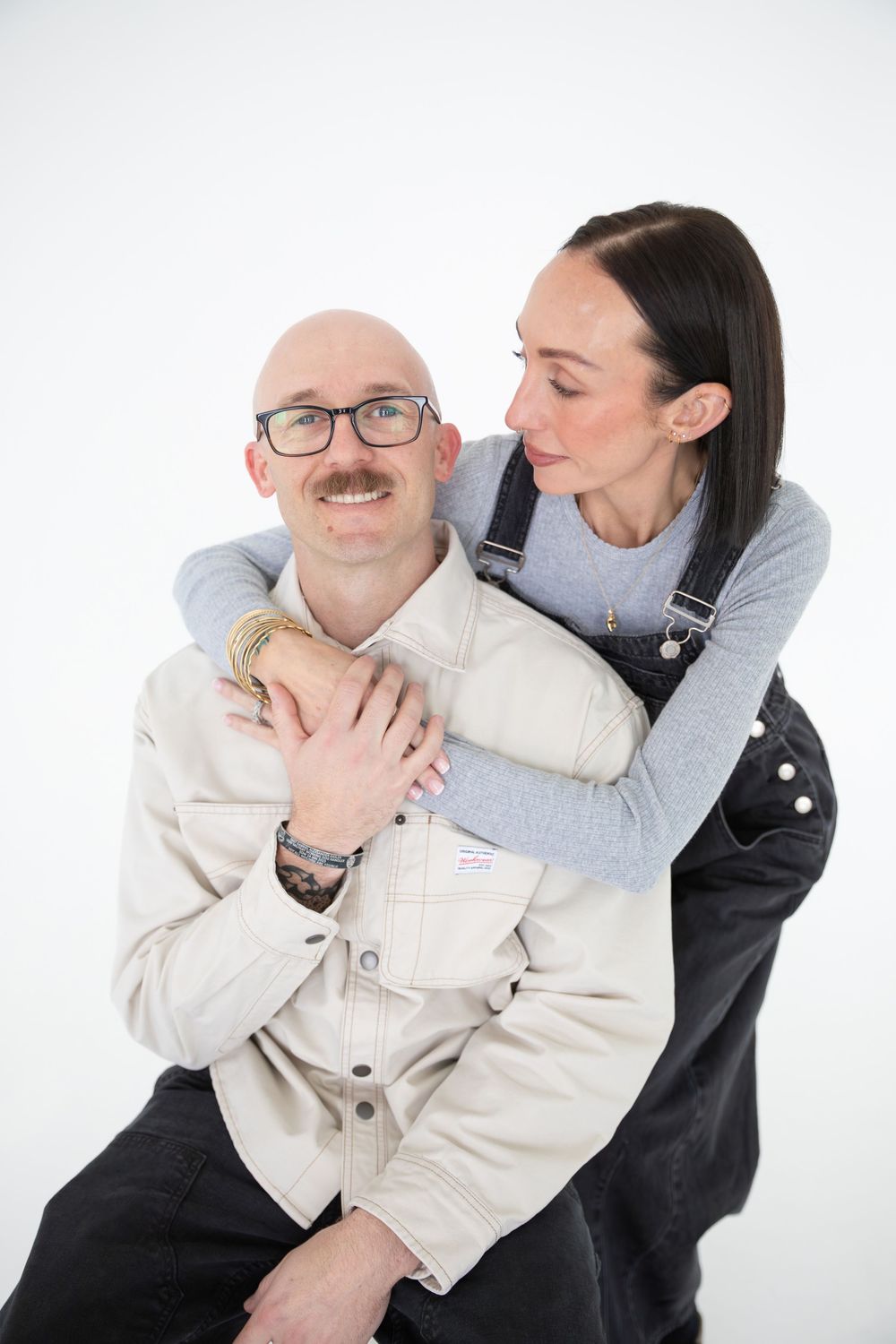 Three sequential photos show two people in contrasting black and white outfits embracing against a white backdrop.