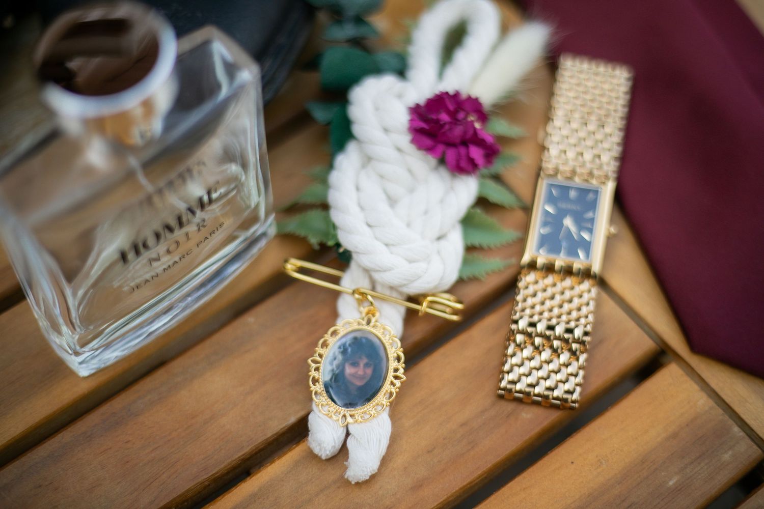 Gold wristwatch and perfume bottle arranged elegantly on a wooden table surface.
