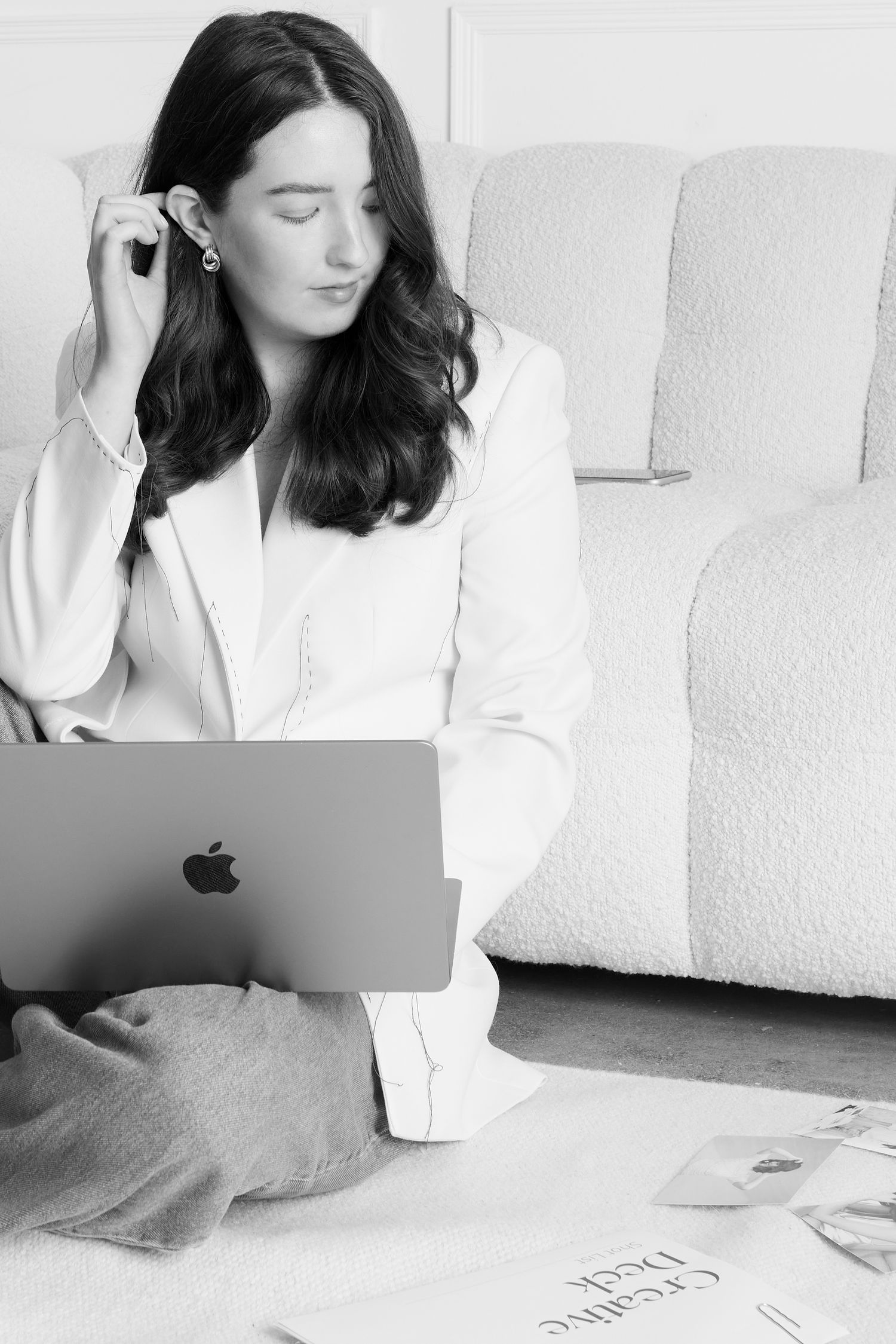 Black and white photo of person working at desk with photographs displayed on wall.
