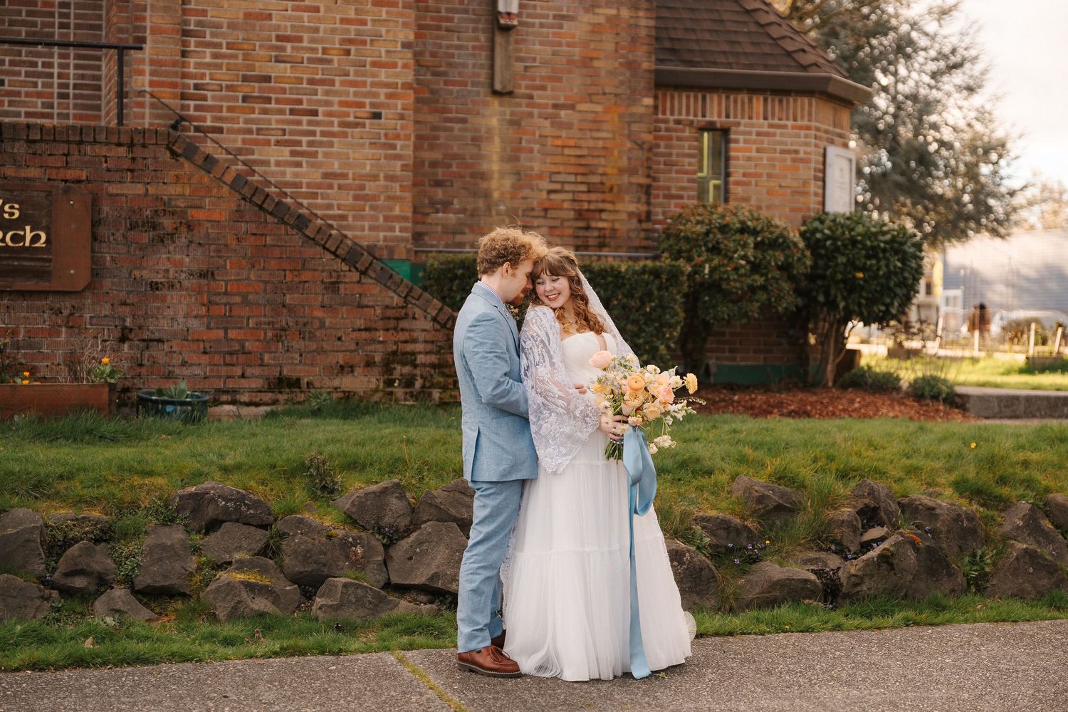 Garden wedding photo with couple on bridge over tranquil pond surrounded by lush greenery.