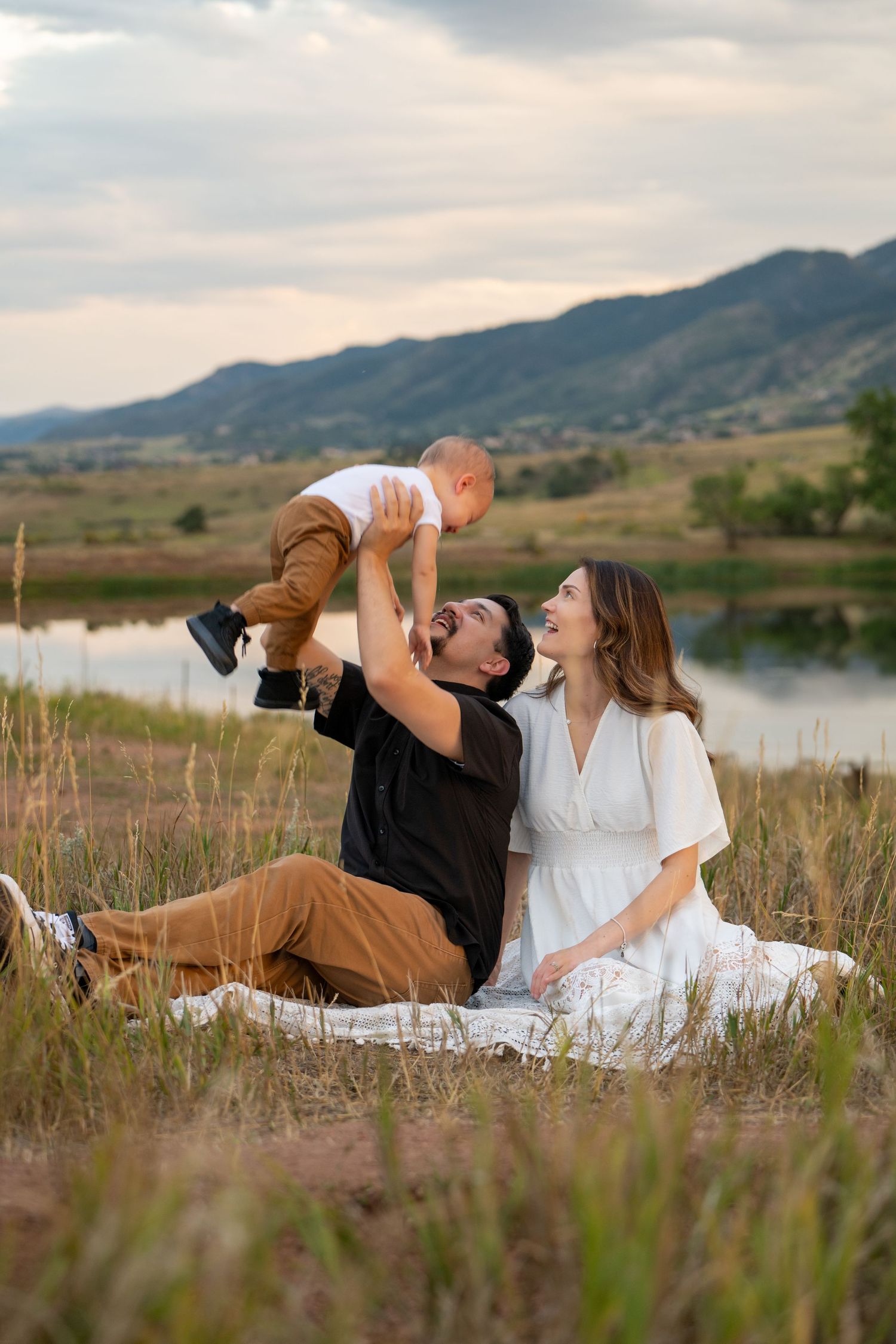Family portrait at sunset by a lake with mountains in background.