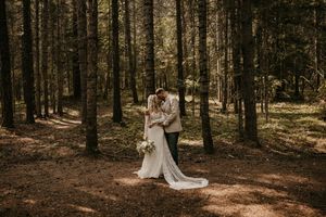Sunlit forest wedding photos with tall trees creating dramatic backdrop.