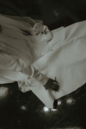 Flowing white wedding dress fabric creates an artistic composition against a dark background.