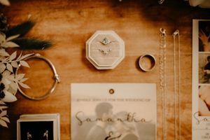 Wedding detail flatlay with rings and decorative elements on wooden background.