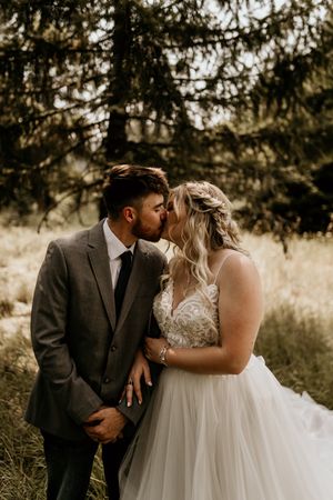 Newlyweds share romantic moments during their outdoor forest wedding.