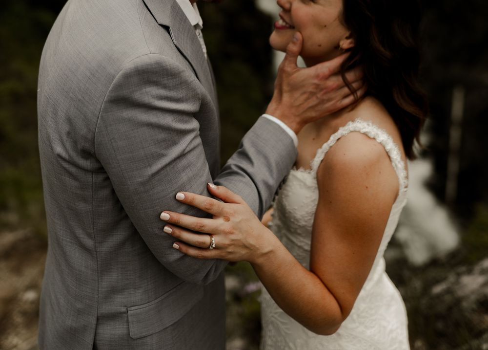 Intimate wedding moment captured between couple in gray suit and white dress.