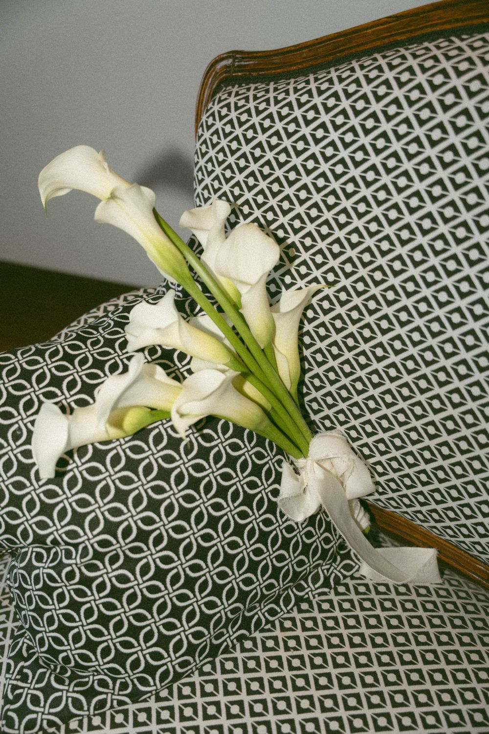 White calla lilies laying on a geometric patterned surface with dark green and white diamond shapes.