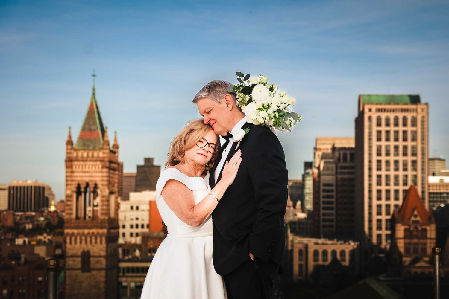 Couple embracing on Lenox Hotel Boston rooftop with Back Bay skyline during golden hour wedding portrait