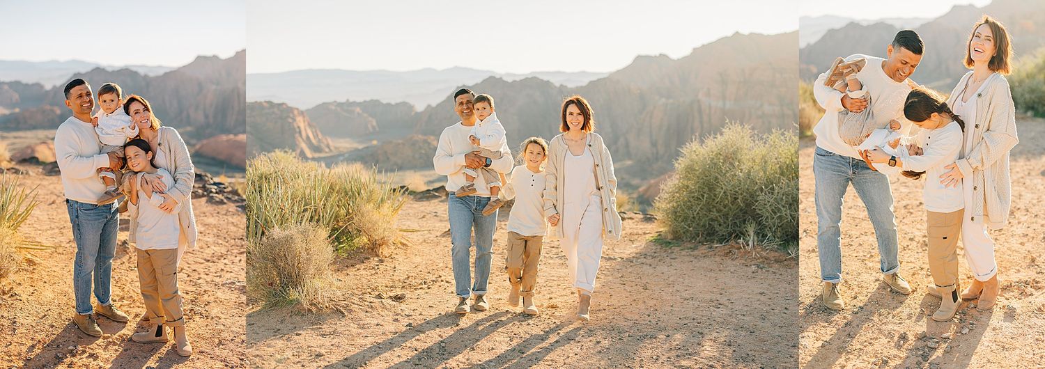 Family posing together in a sunny desert setting with sandy terrain and rocky mountains in the background.