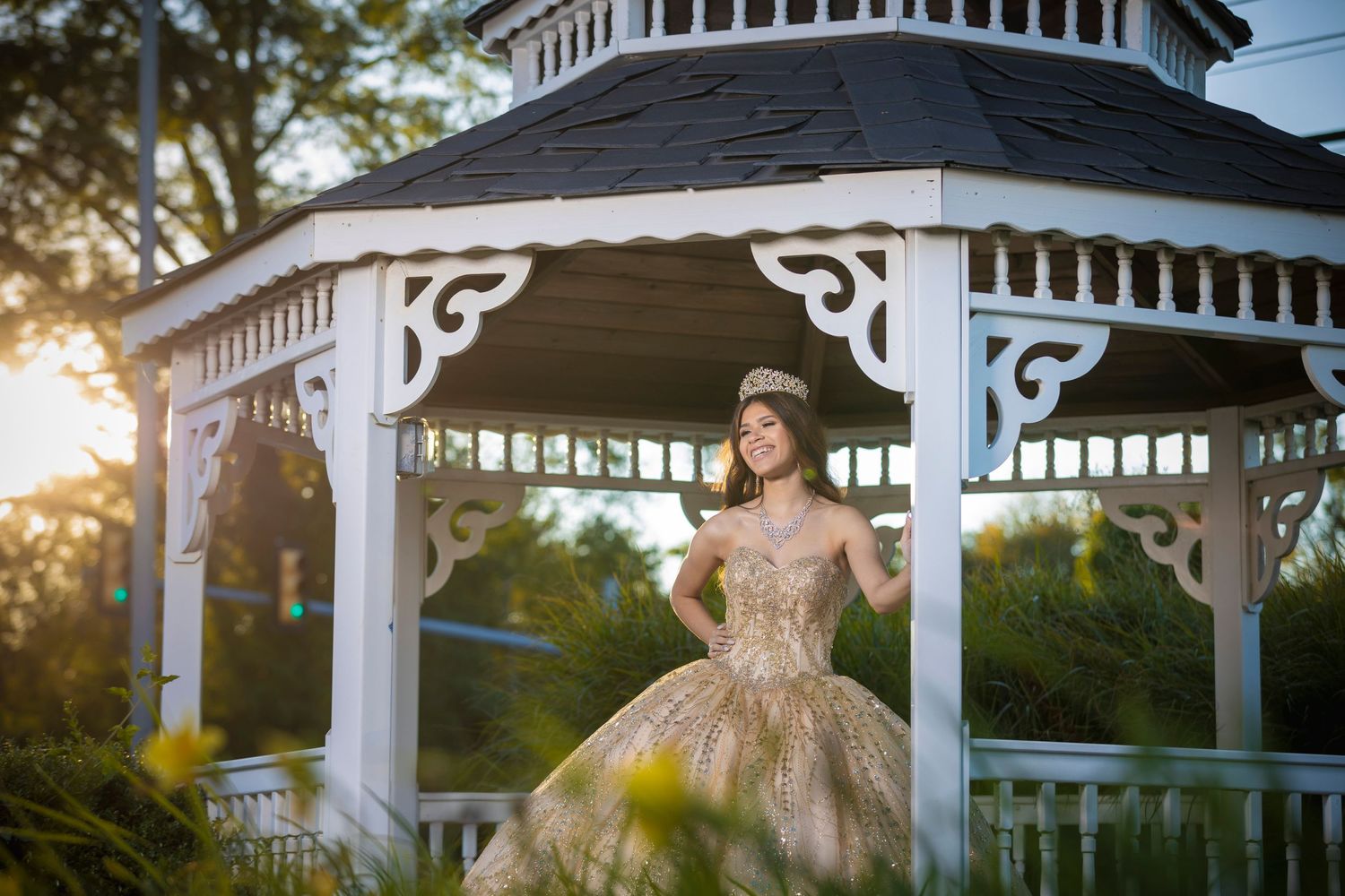 Dreamy sunset photograph at a white gazebo featuring a formal ball gown.
