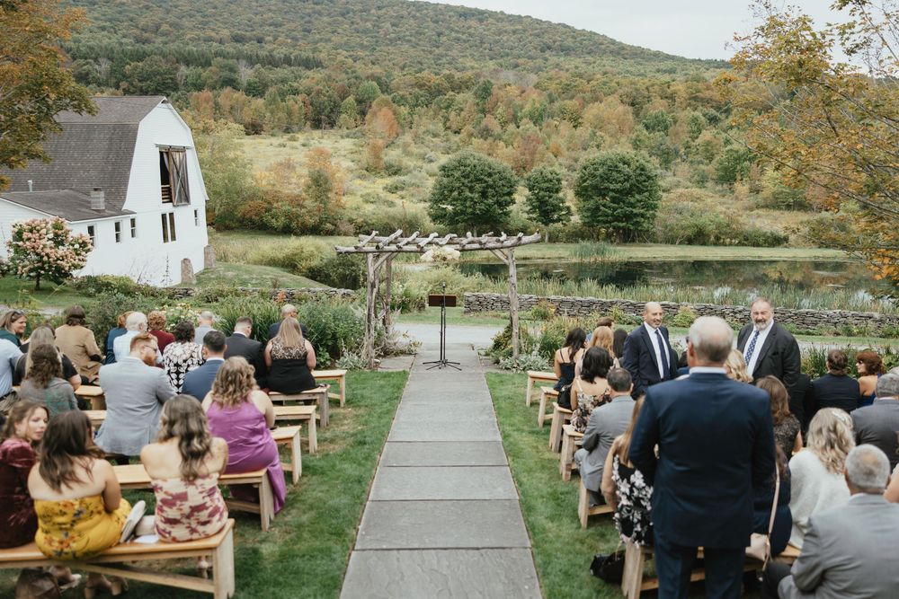 Wedding guests seated outdoors at a rustic mountain venue during an autumn ceremony.