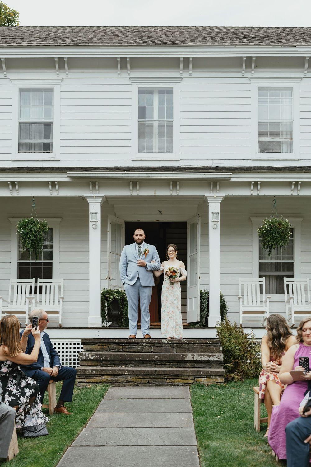 A series of wedding photos taken in front of a white colonial style house with a covered porch and stone steps.