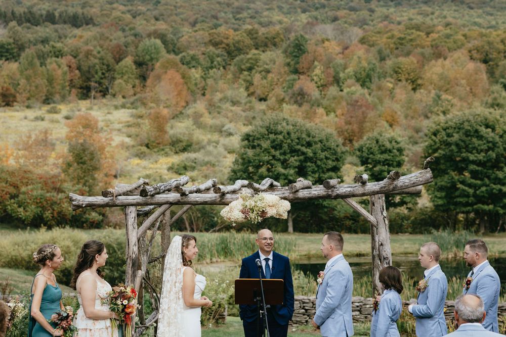 Wedding party stands in line during outdoor ceremony against backdrop of desert mountains and sage brush.