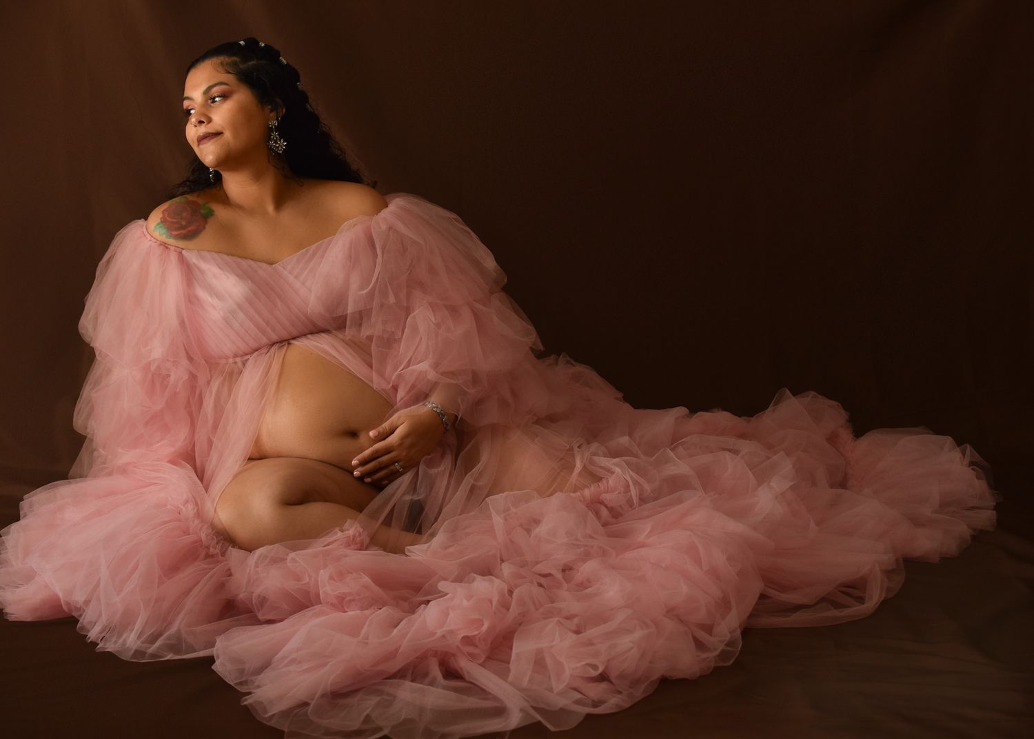 maternity, pink dress, looking out window, brown backdrop, sitting on the ground