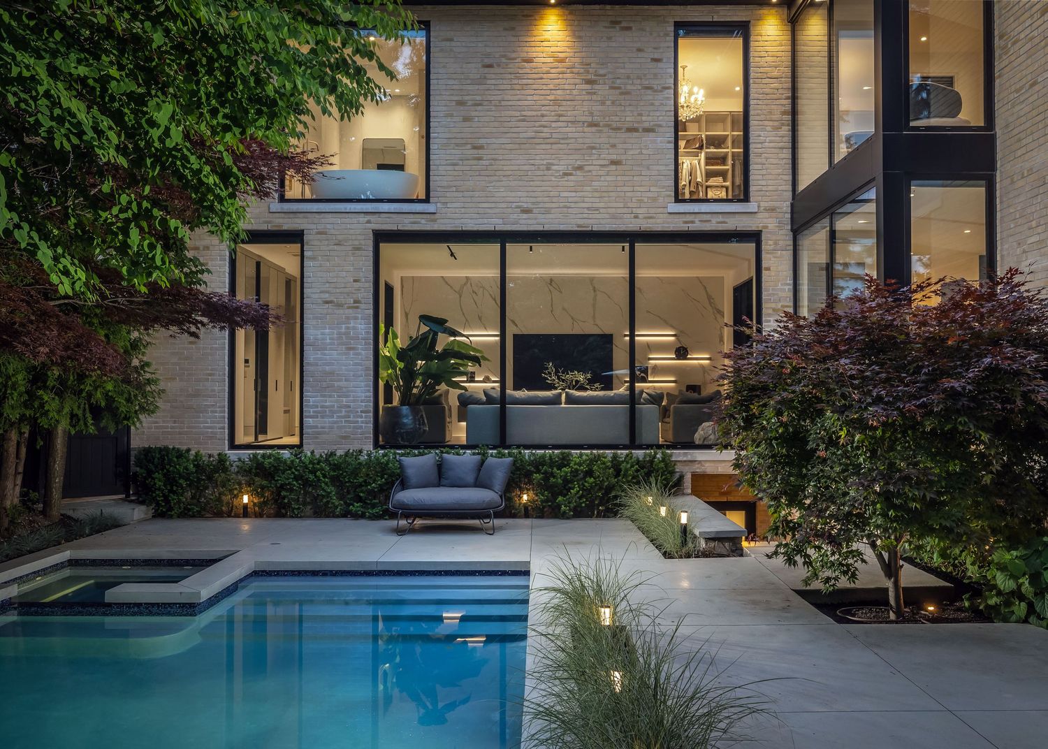 Modern house exterior with swimming pool and landscaped garden at dusk.