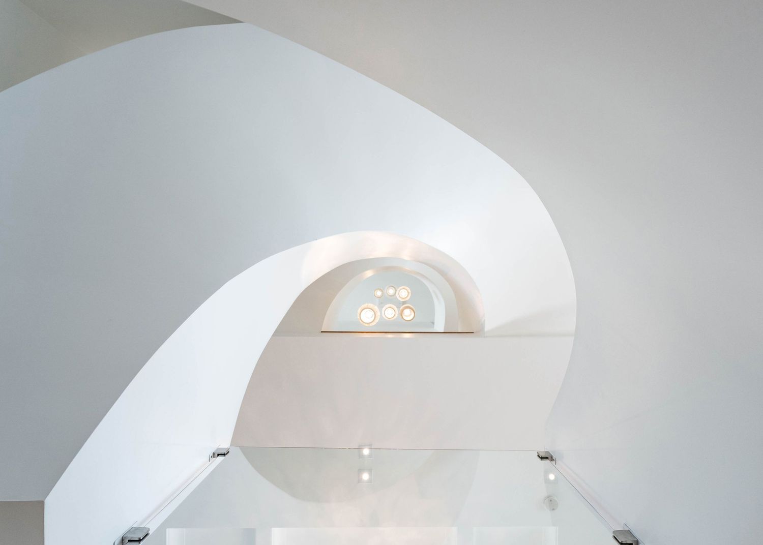 Minimalist white curved architectural space with arched window detail.