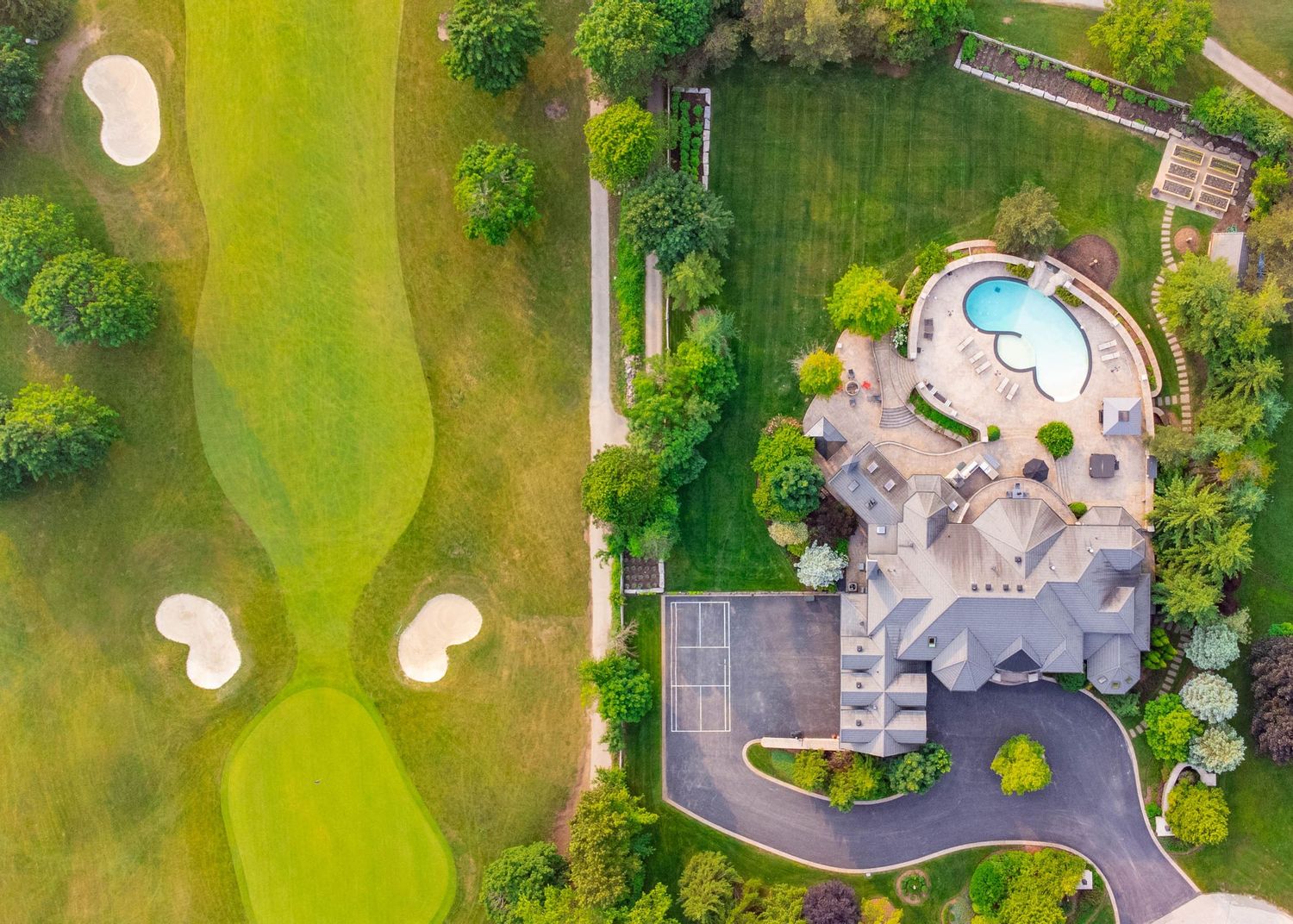 Aerial view of Blue Springs Golf Club with sand bunkers and a curved swimming pool area surrounded by landscaping.