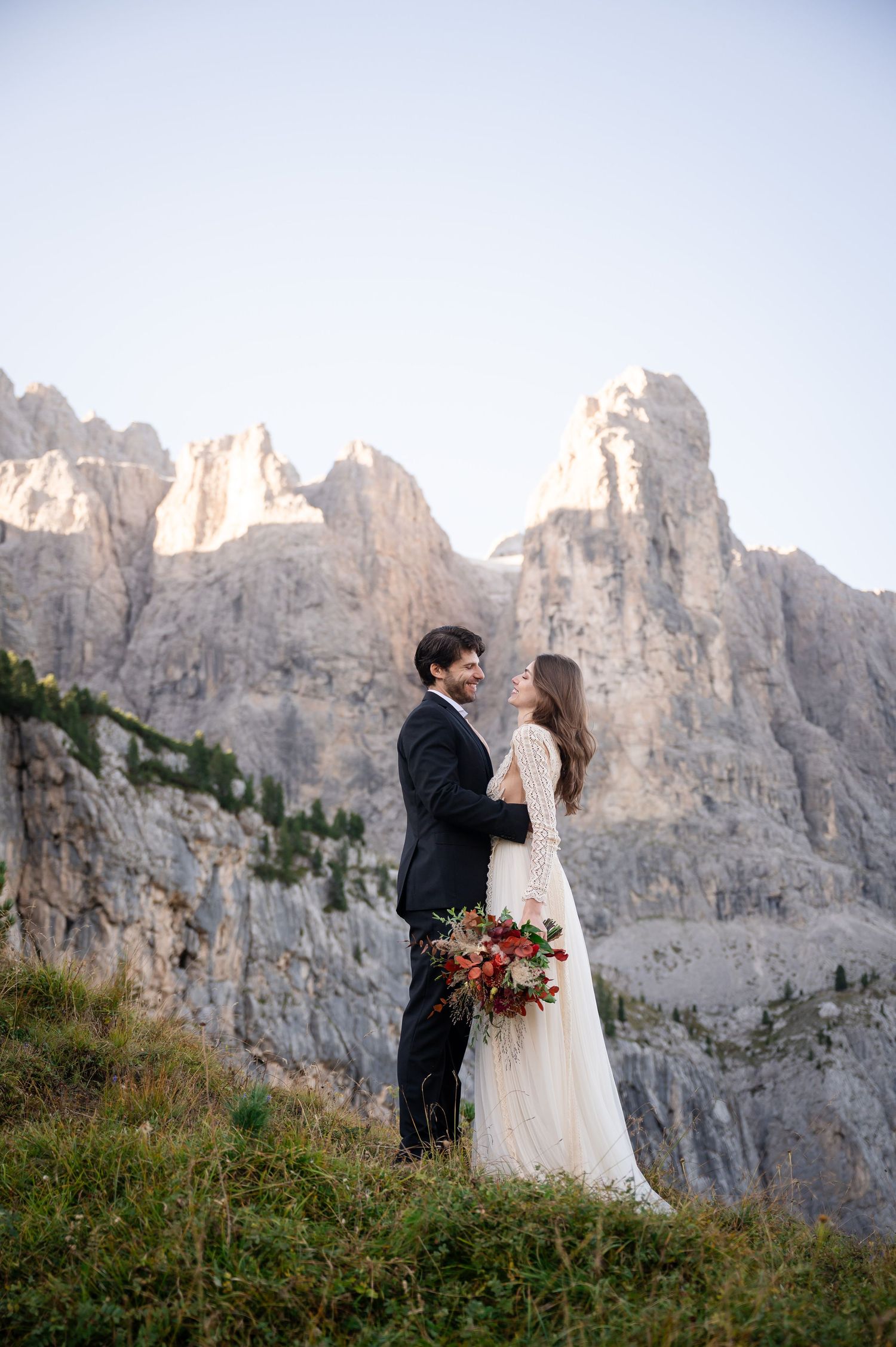 A couple shares an intimate moment against dramatic mountain cliffs during their wedding ceremony in the Dolomites.