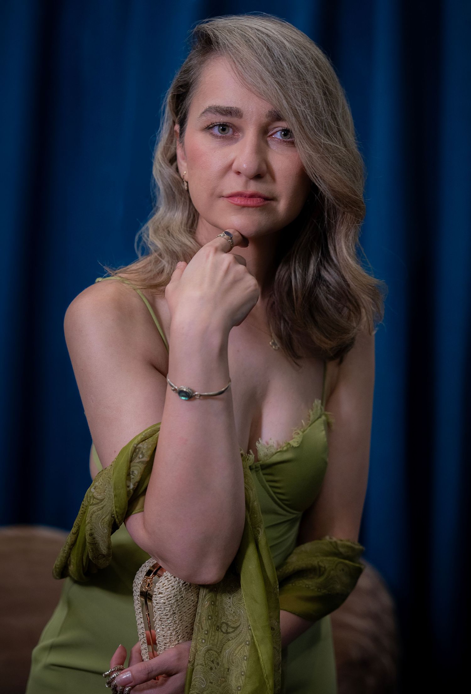 Artistic portrait series of woman in olive green dress against blue backdrop.
