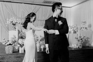 Bride and groom share a tender moment on the dance floor before floral wedding backdrop.