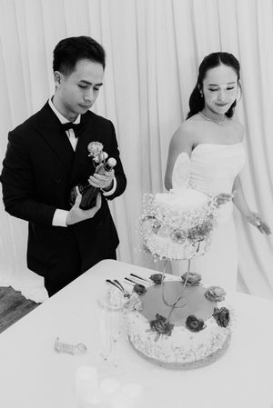 Bride and groom cutting their elegant tiered wedding cake decorated with roses at their wedding reception.