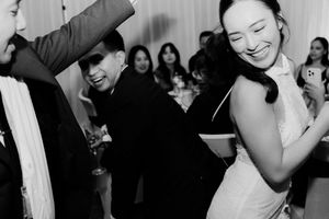 Bride and groom dancing and laughing with guests during their fun wedding reception celebration.