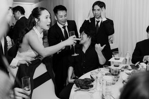 Bride toasting champagne with a seated wedding guest during the lively wedding reception dinner.