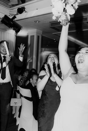 Joyful guest triumphantly catches the bridal bouquet toss at wedding reception.