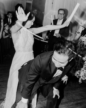 Black and white photo of bride and groom doing the limbo dance at their wedding reception.