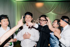 Excited wedding guests wearing headbands celebrating and dancing together at a festive reception.
