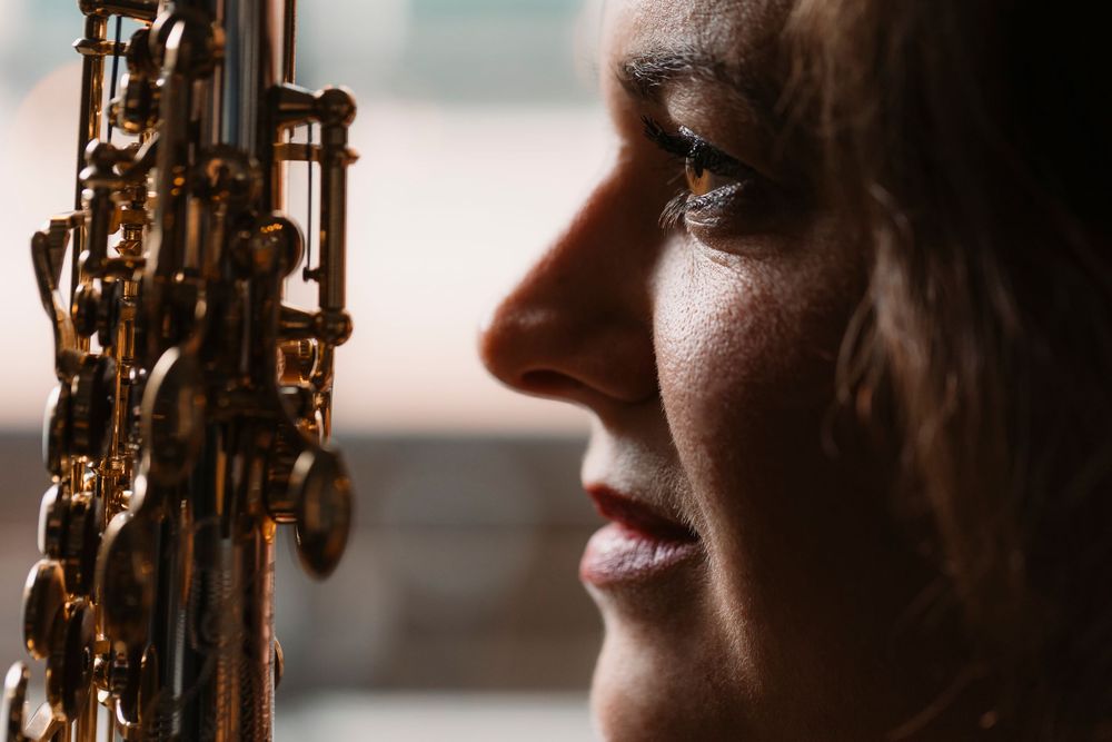 Close-up profile view of musician with saxophone in dramatic lighting.