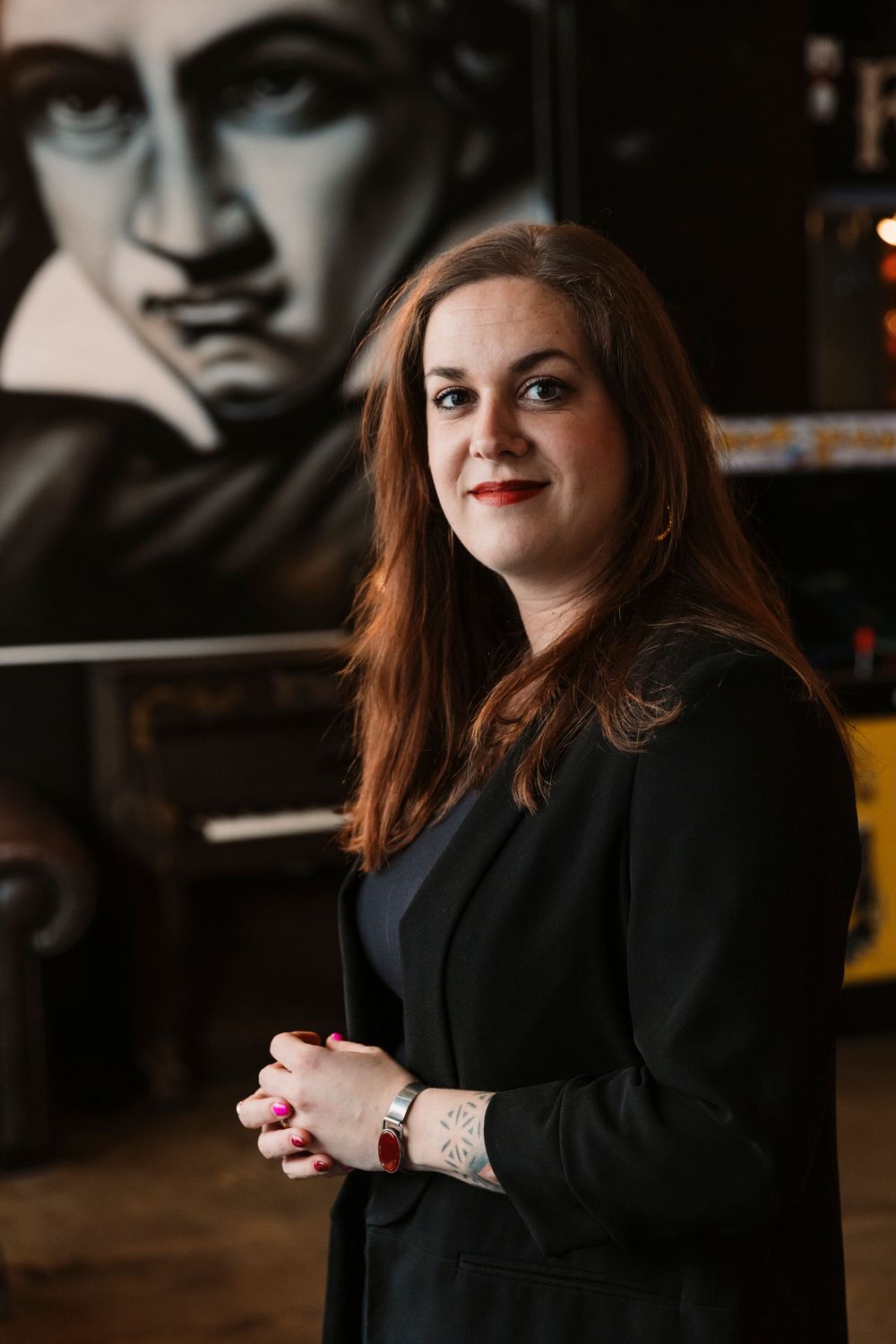 Musician standing in front of a Beethoven portrait in a dark artistic setting.